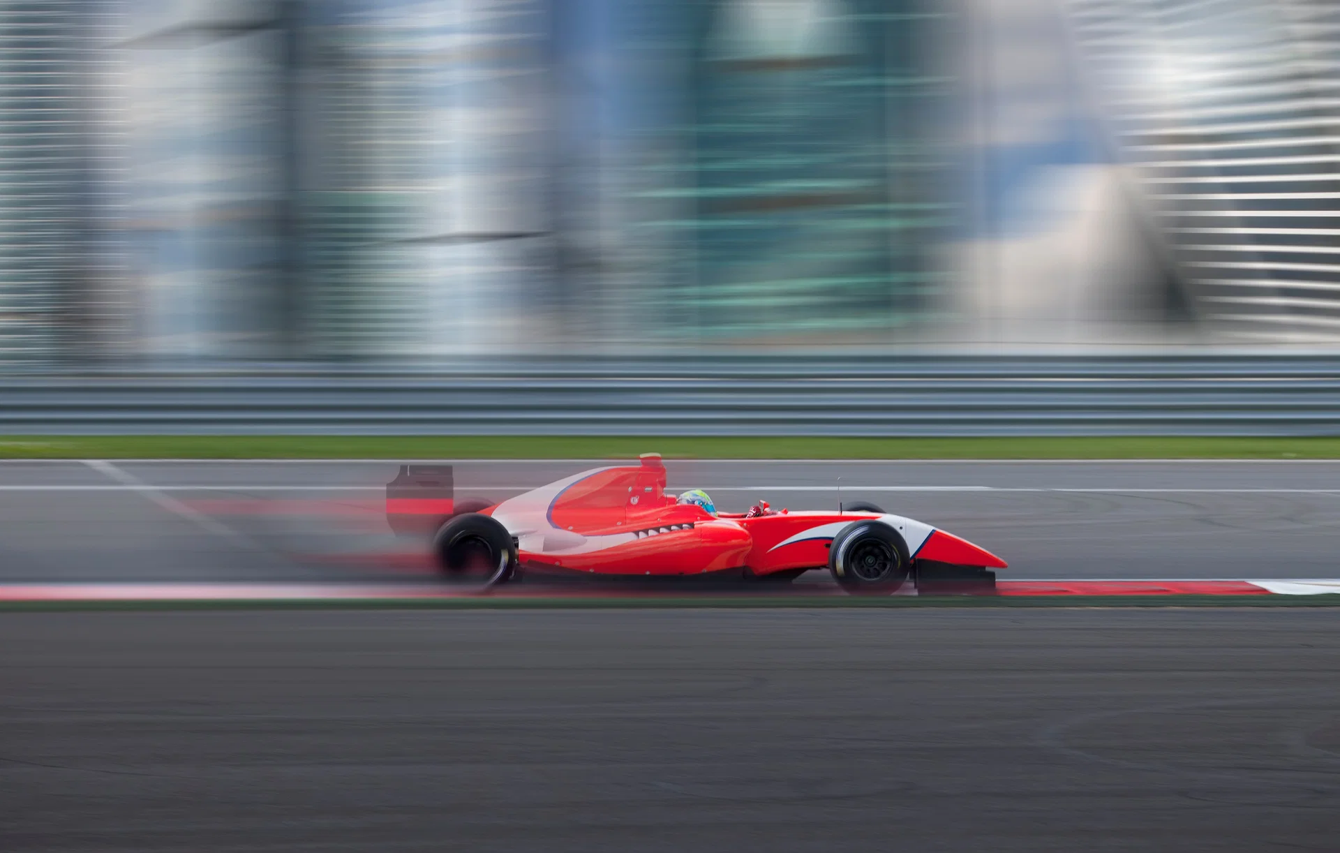 Roter Formel-Rennwagen fährt mit Bewegungsunschärfe über eine Rennstrecke