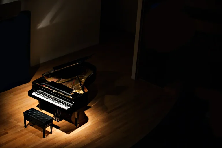 Konzertflügel im Spotlicht auf Holzboden in einem dunklen Saal