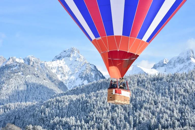 Heissluftballon mit Passagieren über verschneiten Wäldern vor Alpengipfeln - Marketing-Übersetzungen für internationale Märkte