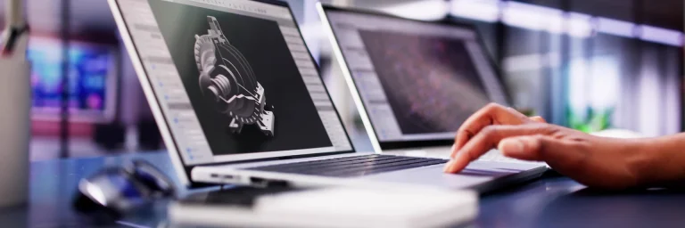 Hand auf einem Laptop-Touchpad, auf dem Bildschirm das 3D-Modell eines Maschinenteils